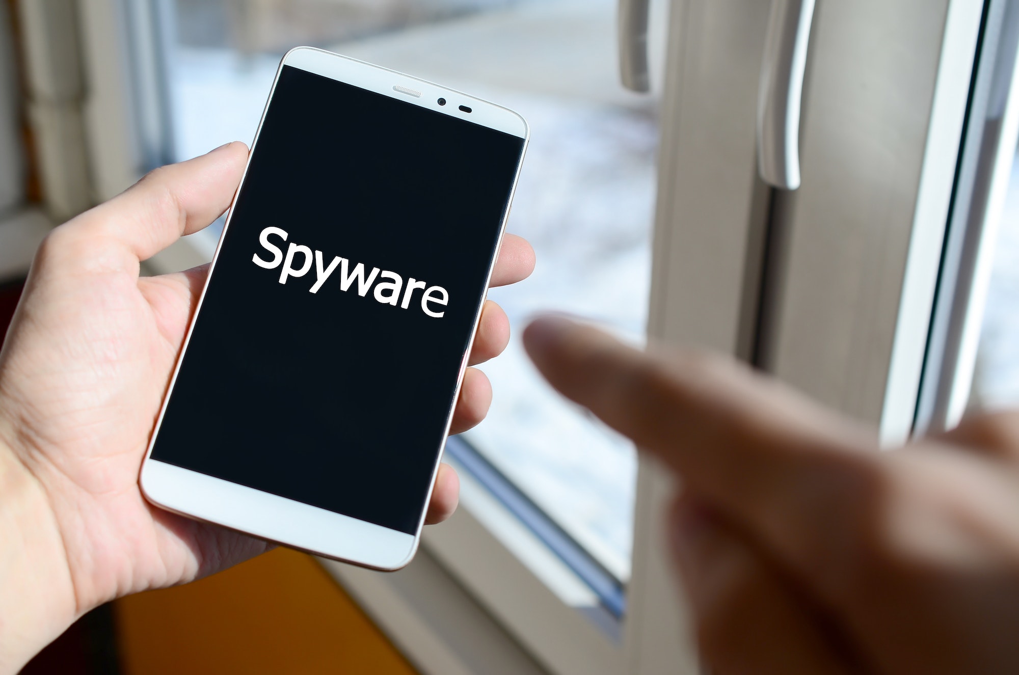 A person sees a white inscription on a black smartphone display that holds in his hand. Spyware